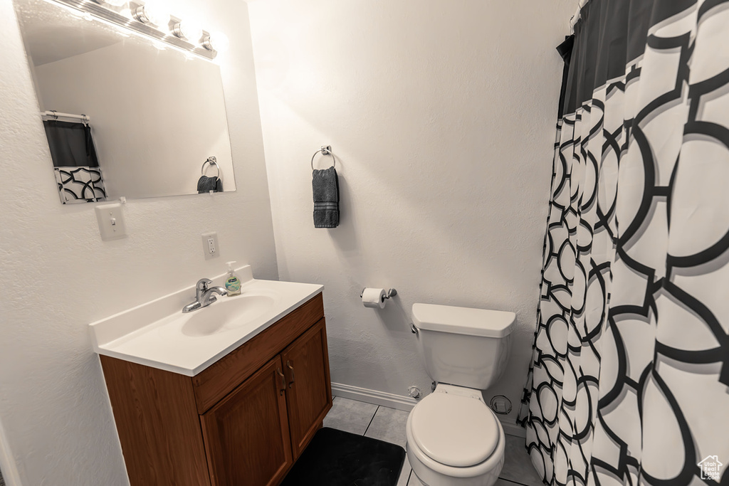Bathroom featuring tile patterned floors, toilet, a shower with shower curtain, baseboards, and vanity