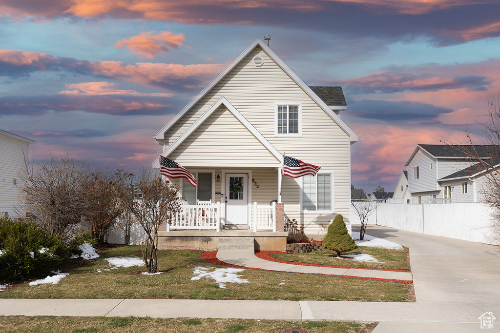 View of front of home featuring a yard, covered porch, and fence