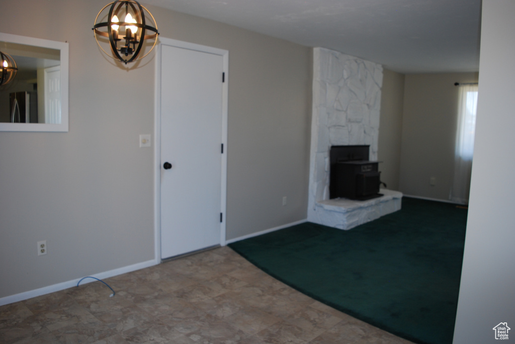 Unfurnished living room featuring a chandelier and a wood stove