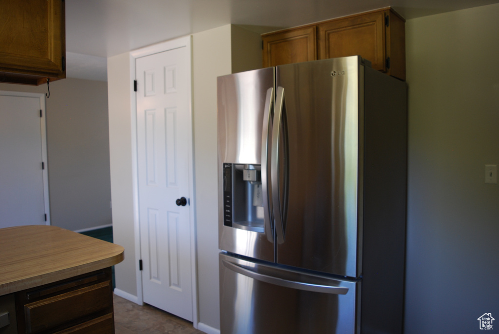 Kitchen featuring stainless steel refrigerator with ice dispenser and brown cabinetry