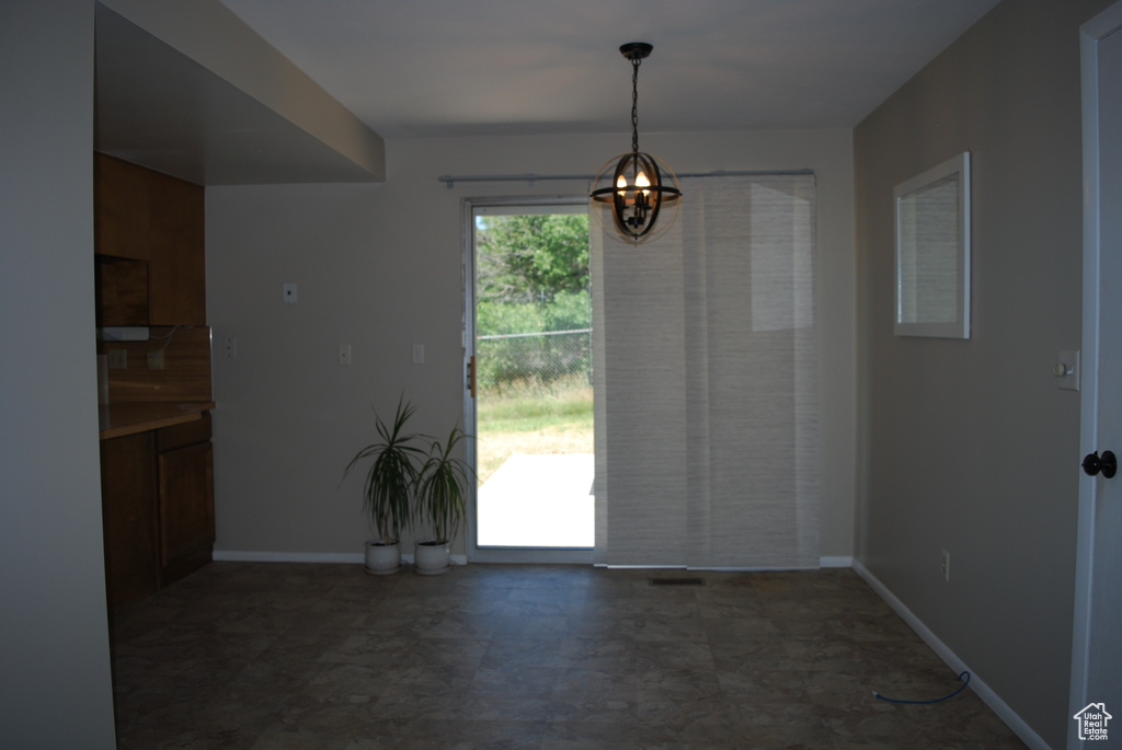 Unfurnished dining area with a chandelier and baseboards