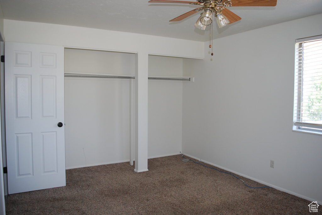 Unfurnished bedroom featuring carpet, multiple windows, two closets, and a ceiling fan