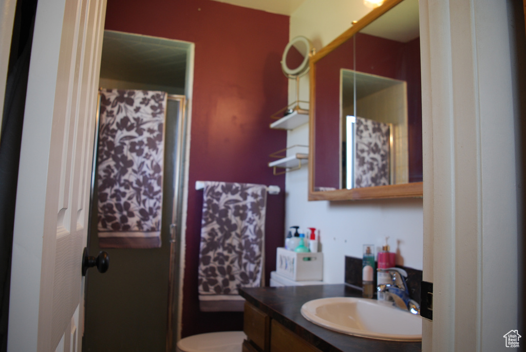 Bathroom featuring toilet, a shower, and vanity