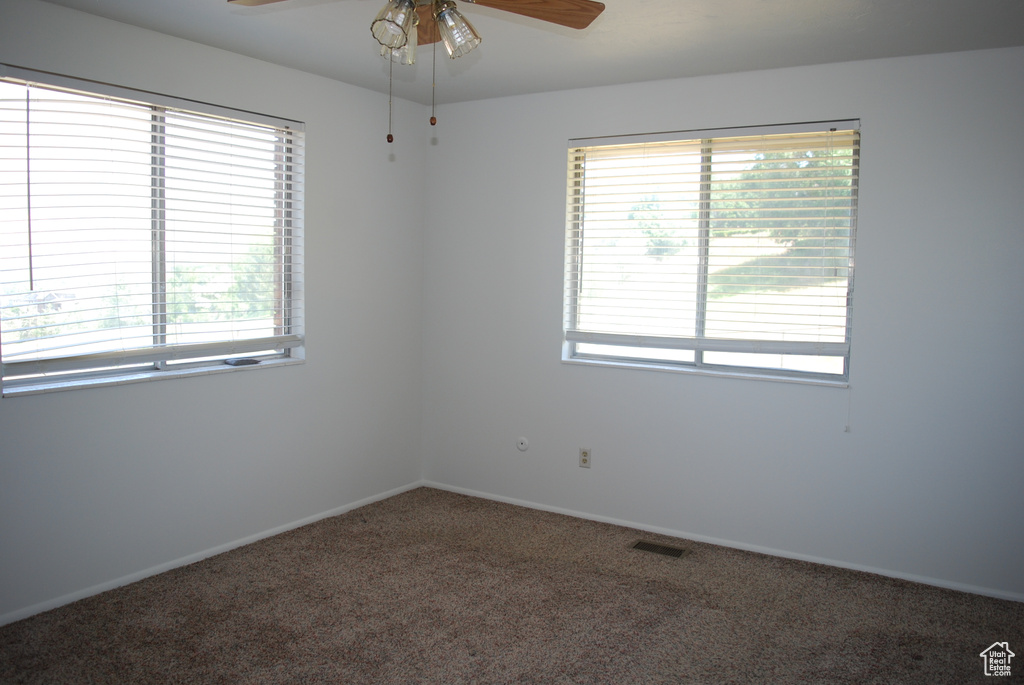 Empty room featuring healthy amount of natural light, carpet flooring, and a ceiling fan