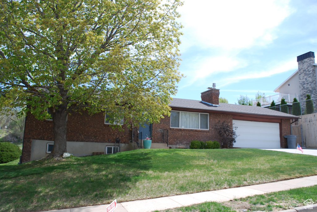 Single story home featuring a front lawn, a garage, central AC unit, driveway, and brick siding