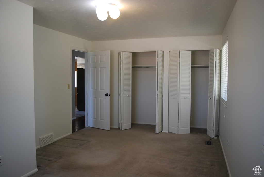 Unfurnished bedroom featuring multiple closets and carpet flooring