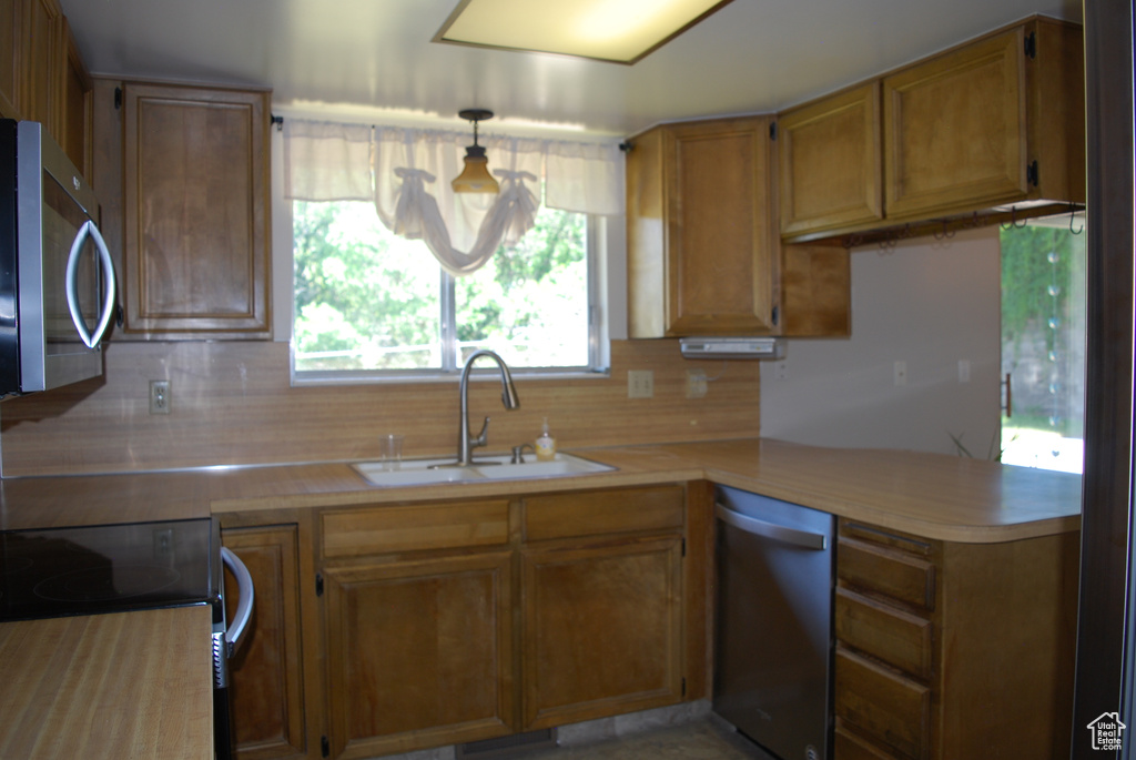 Kitchen featuring appliances with stainless steel finishes, light countertops, tasteful backsplash, and brown cabinets