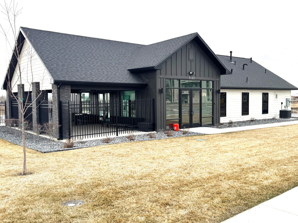 Rear view of property with a patio area, a lawn, board and batten siding, and a shingled roof