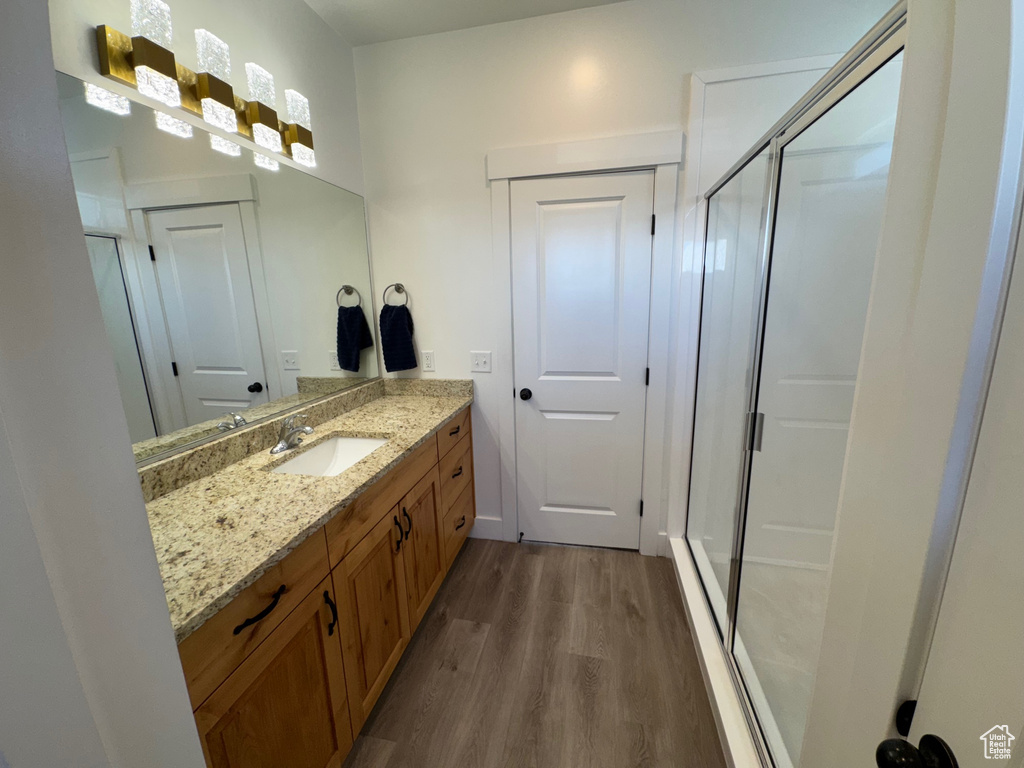 Full bathroom featuring a shower stall, vanity, and wood finished floors