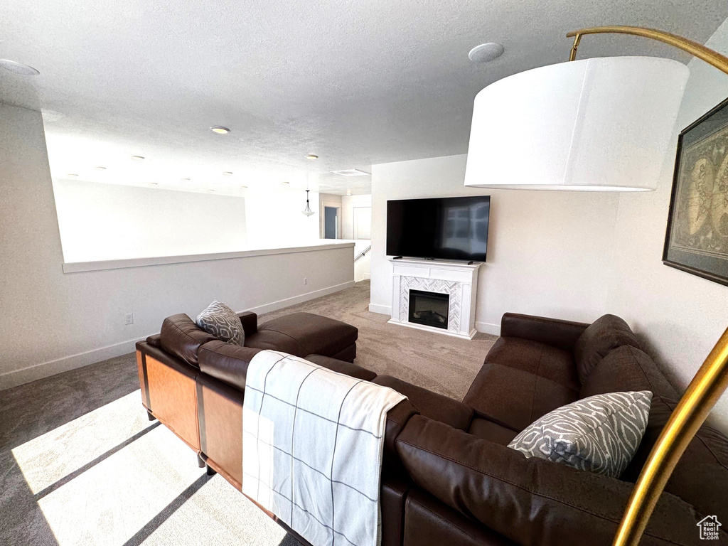 Living area featuring a fireplace, baseboards, carpet floors, and a textured ceiling