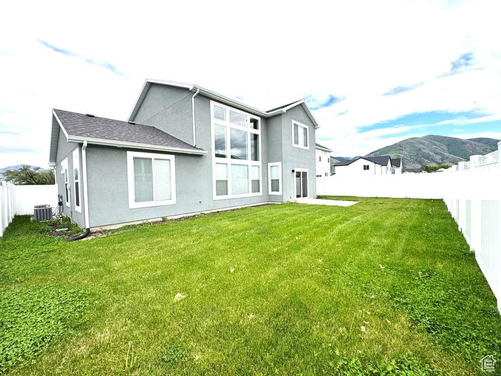 Rear view of property with central AC unit, stucco siding, and a mountain view
