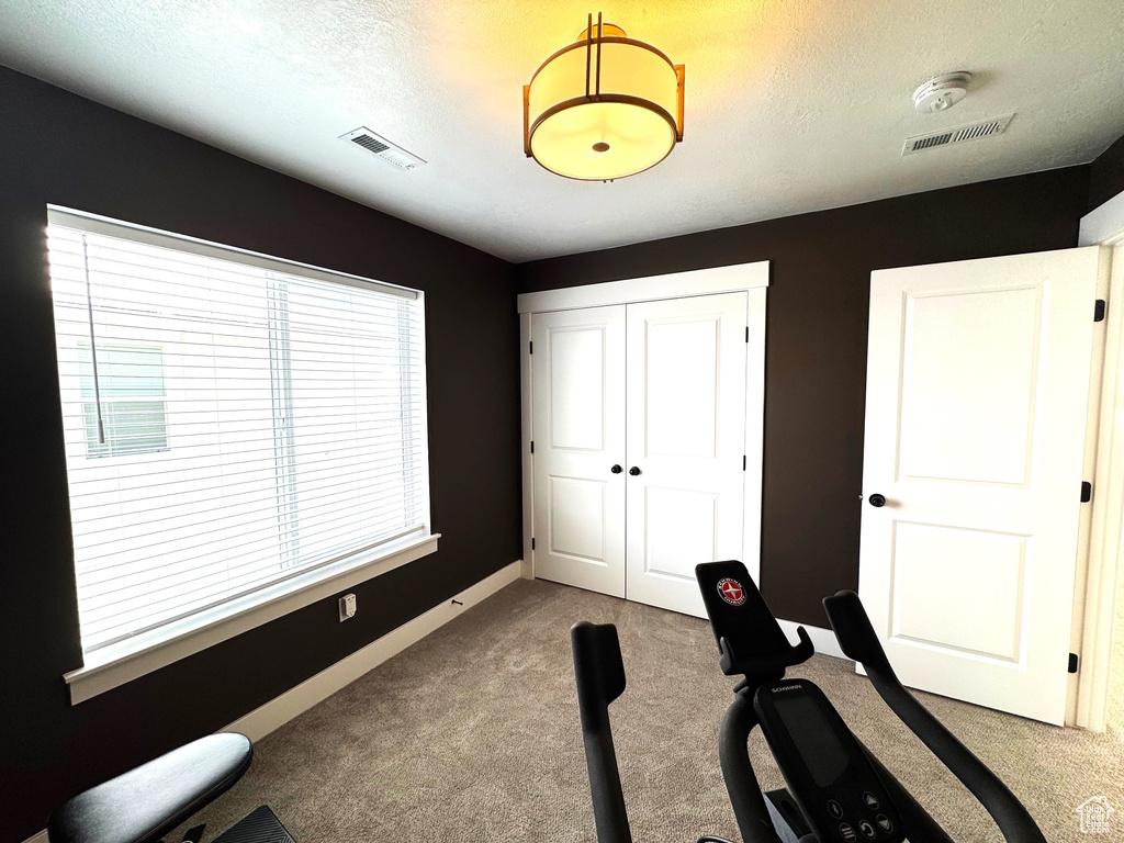 Workout area featuring visible vents, carpet flooring, and a textured ceiling