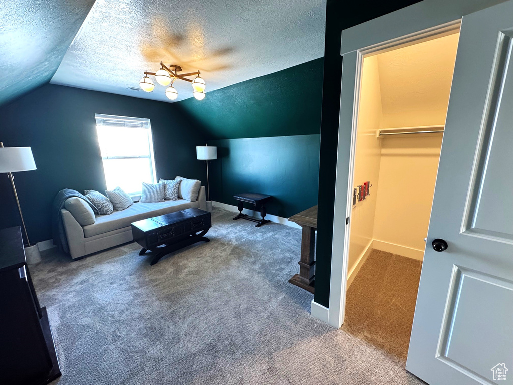 Carpeted living room with lofted ceiling, baseboards, and a textured ceiling