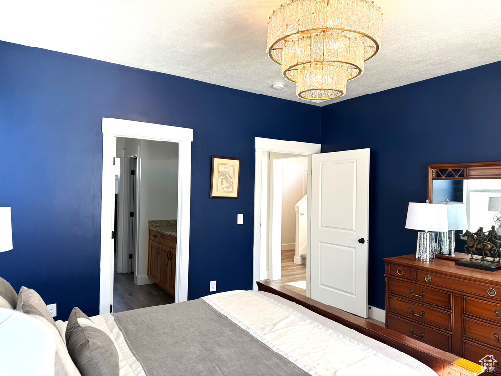 Bedroom with a textured ceiling, an inviting chandelier, and wood finished floors