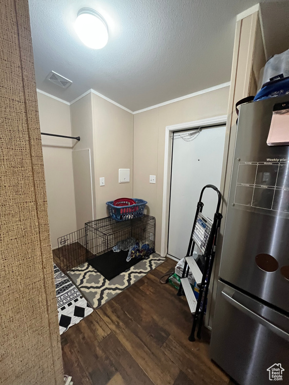 Kitchen with wood finished floors, visible vents, freestanding refrigerator, ornamental molding, and a textured ceiling