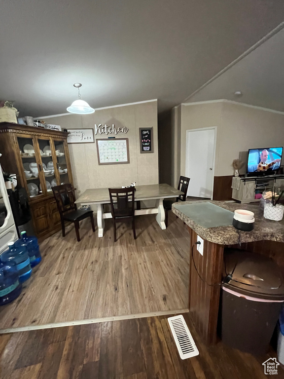 Dining area featuring vaulted ceiling, visible vents, ornamental molding, and wood finished floors