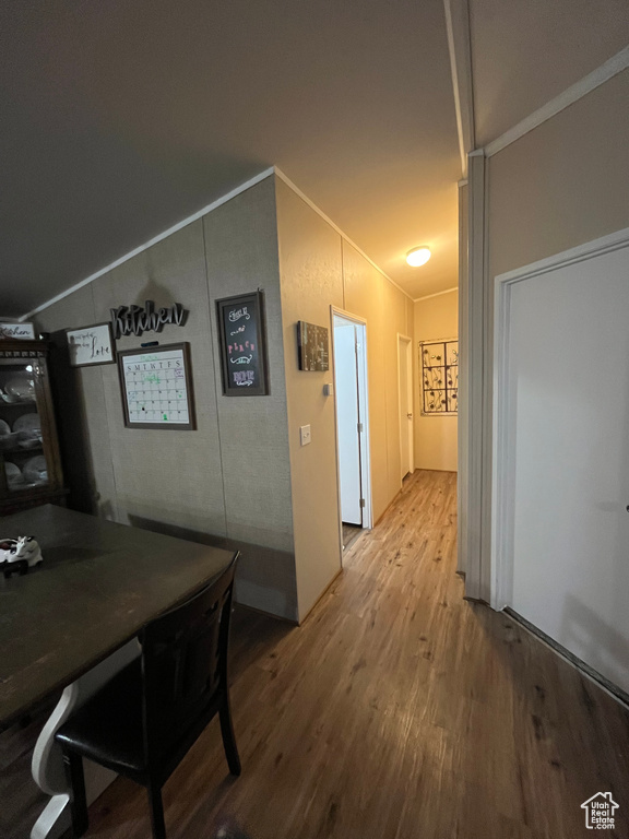 Hall with wood finished floors, ornamental molding, and vaulted ceiling