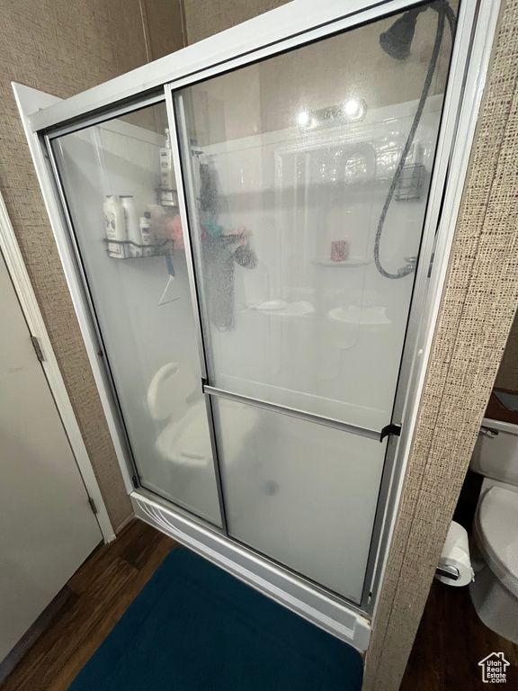 Bathroom with a stall shower, toilet, and wood finished floors