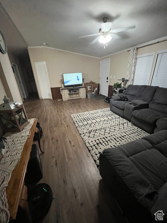 Living room with dark wood-type flooring, a ceiling fan, a textured ceiling, crown molding, and vaulted ceiling