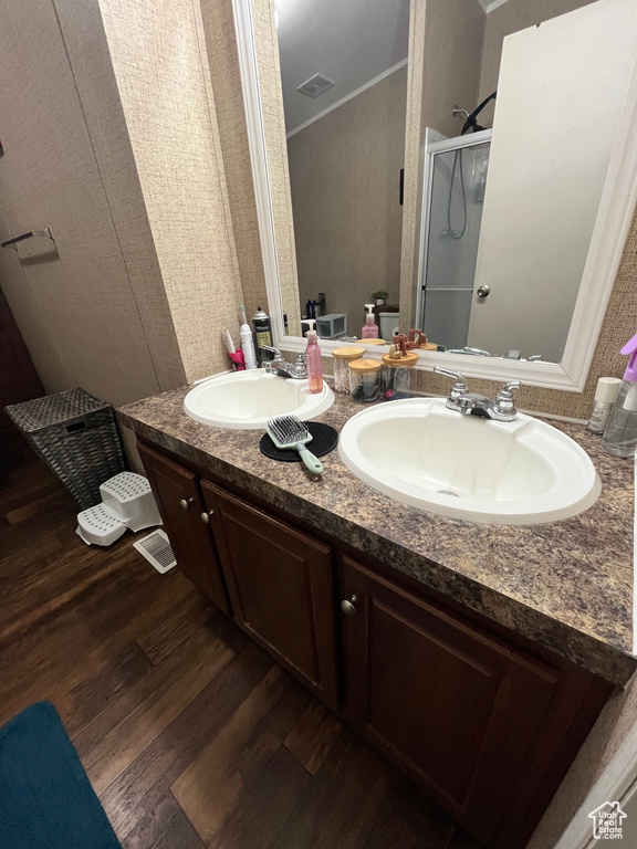 Bathroom with a sink, wood finished floors, a shower stall, and crown molding