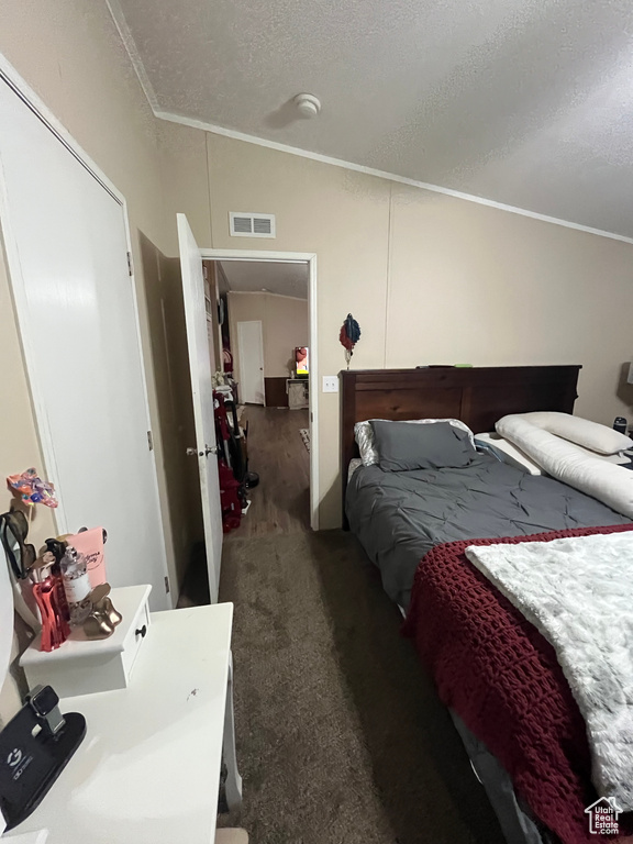 Bedroom with visible vents, a textured ceiling, carpet, and ornamental molding