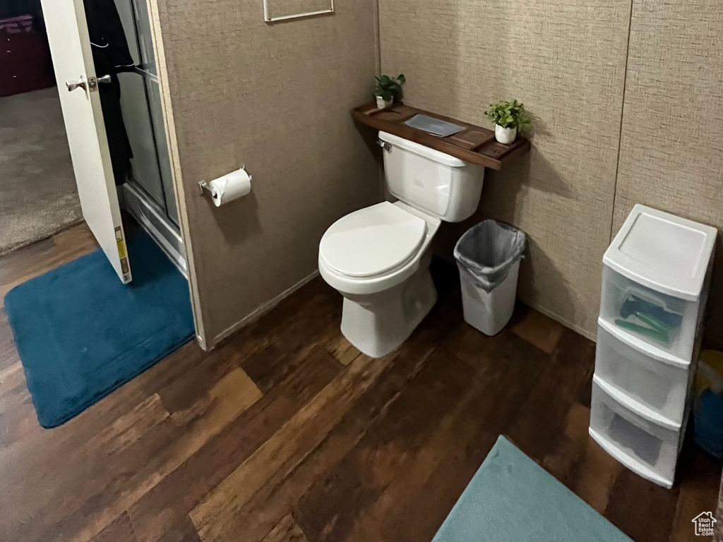 Full bathroom with a stall shower, toilet, wood finished floors, and crown molding