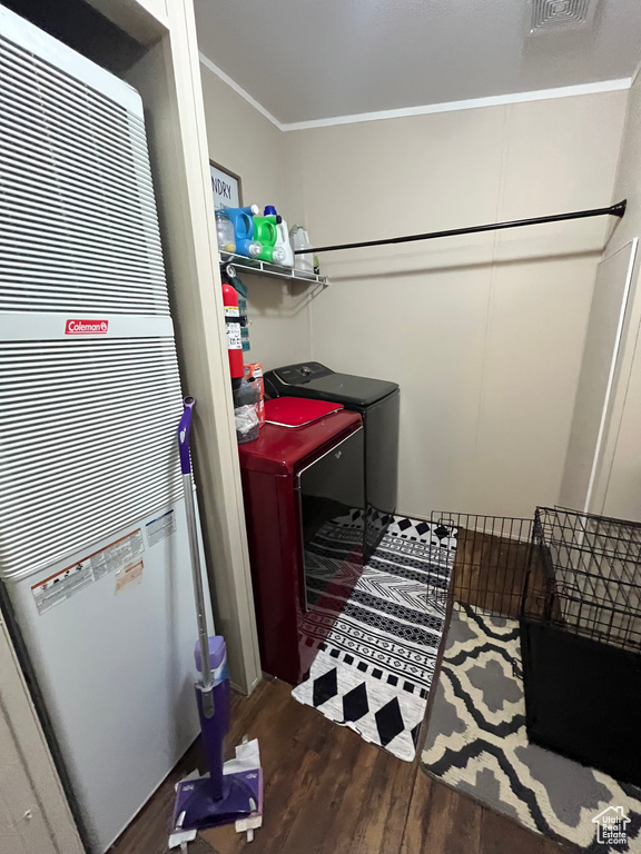 Laundry area with visible vents, ornamental molding, wood finished floors, a heating unit, and laundry area
