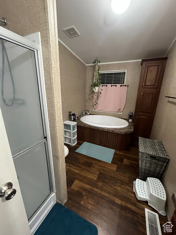 Full bath with visible vents, a garden tub, a stall shower, wood finished floors, and vaulted ceiling
