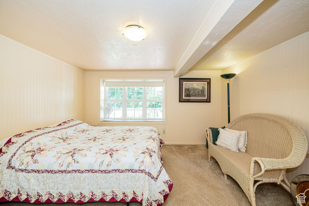 Carpeted bedroom featuring a textured ceiling, wood walls, and baseboards