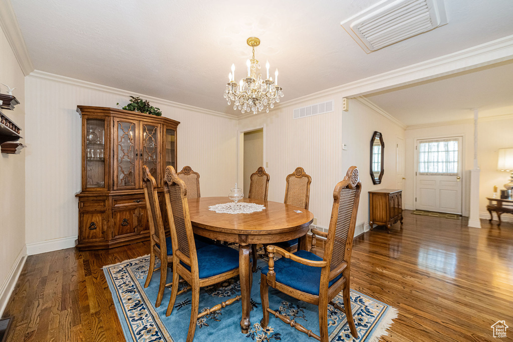 Dining space featuring a chandelier, ornamental molding, wood finished floors, and baseboards