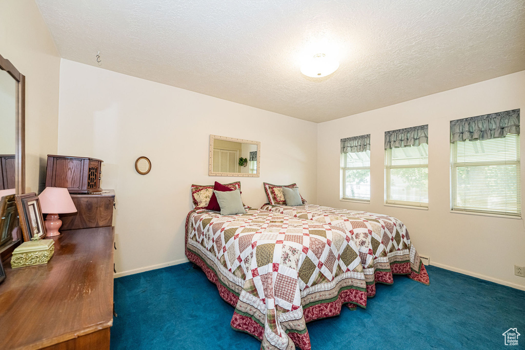 Carpeted bedroom featuring baseboards and a textured ceiling