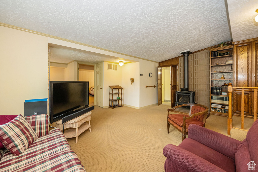 Living room featuring a textured ceiling, vaulted ceiling, a wood stove, carpet, and baseboards