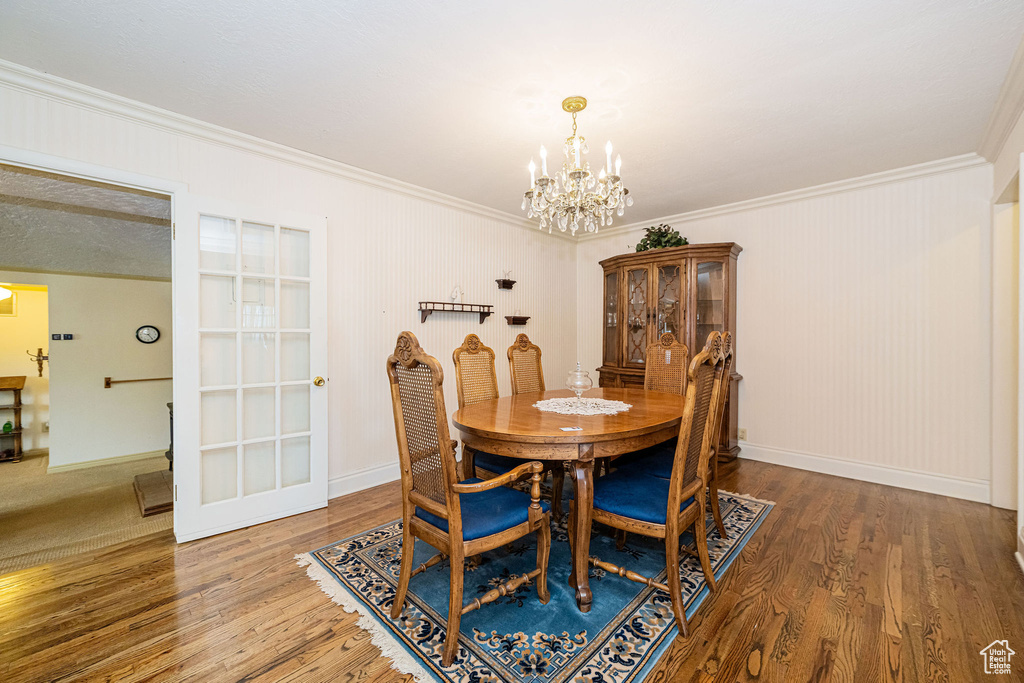 Dining area featuring a chandelier, crown molding, wood finished floors, and baseboards