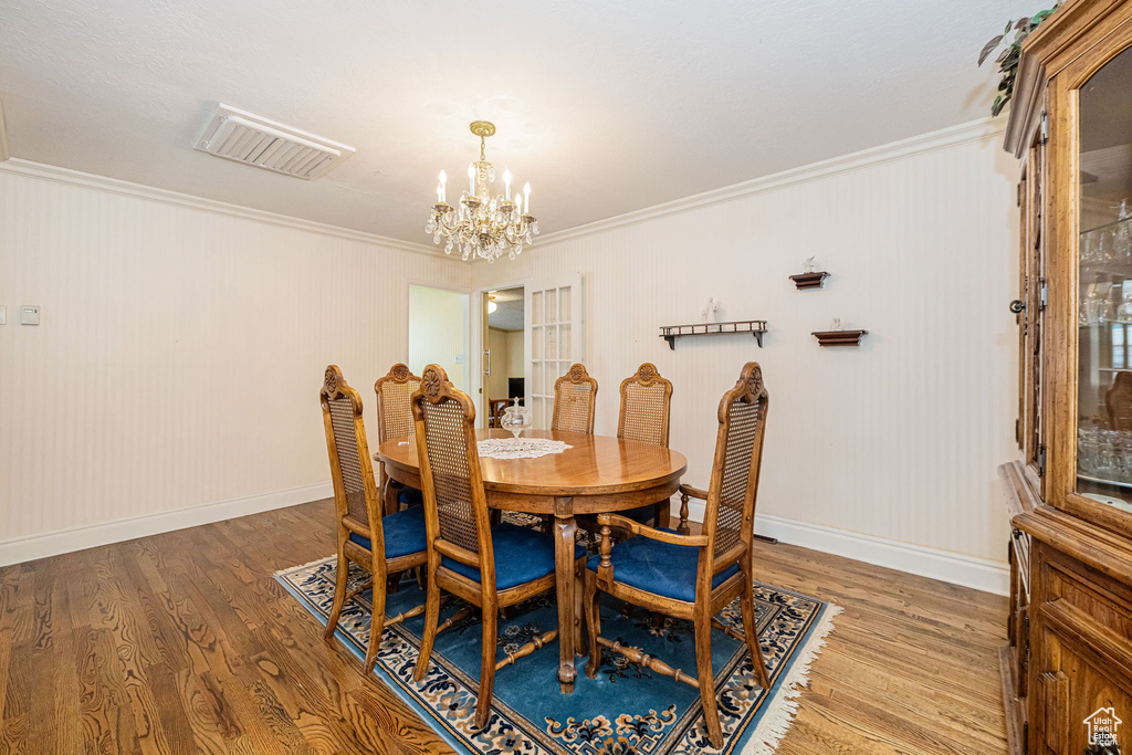 Dining area featuring a chandelier, crown molding, wood finished floors, and baseboards