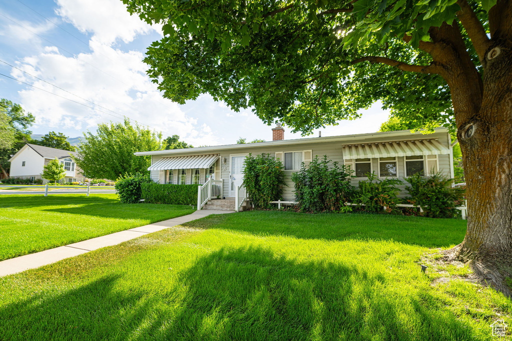 Single story home with a chimney and a front lawn