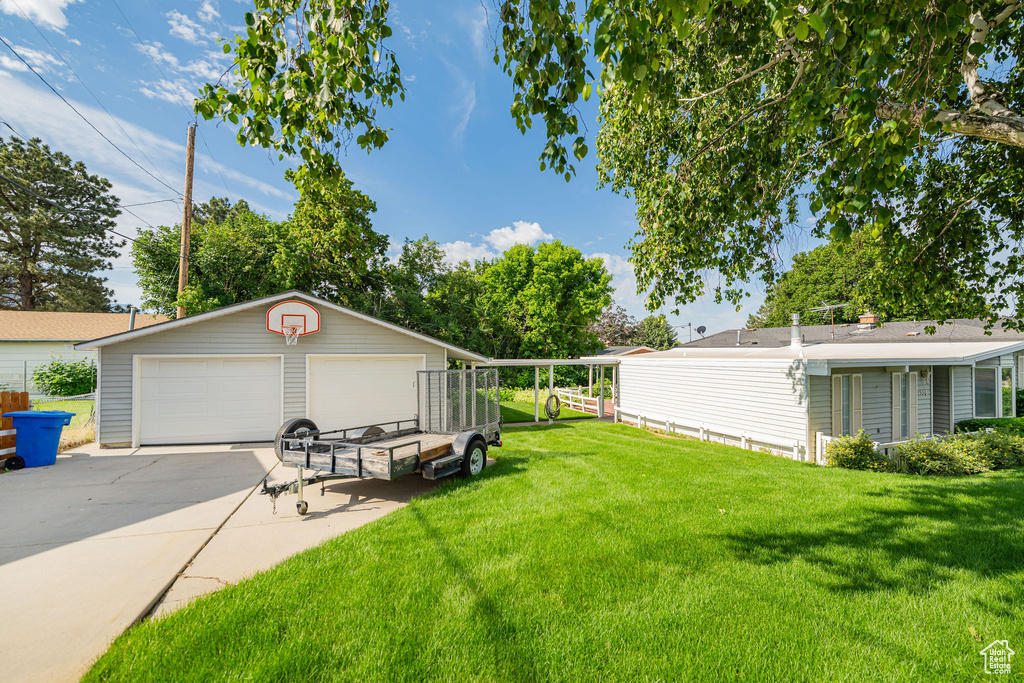 View of green lawn featuring a garage and an outbuilding