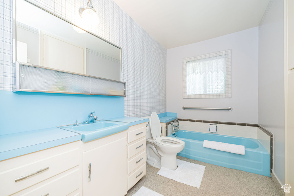 Bathroom with a garden tub, toilet, vanity, and tile walls