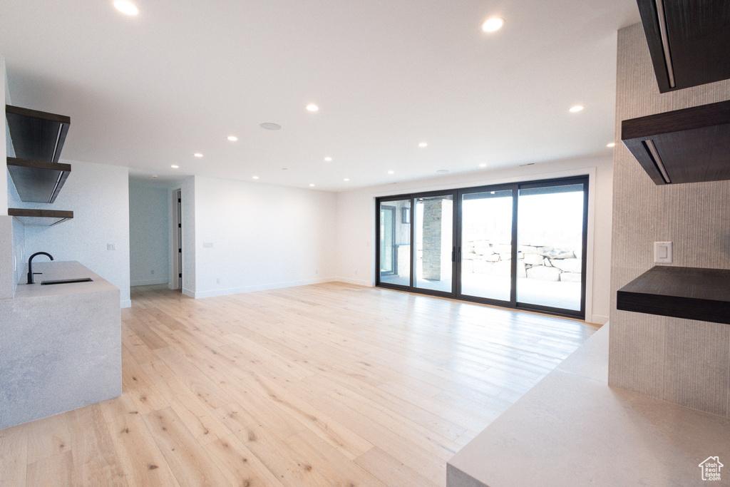 Unfurnished living room featuring light wood-type flooring, a sink, and recessed lighting