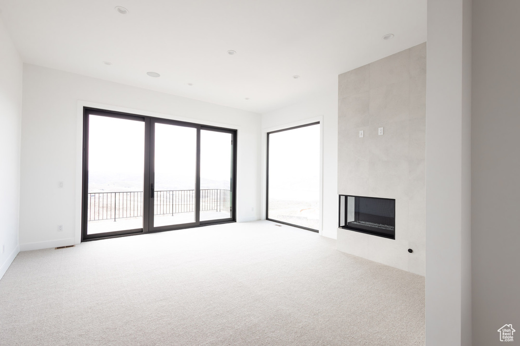 Unfurnished living room with a fireplace and light carpet