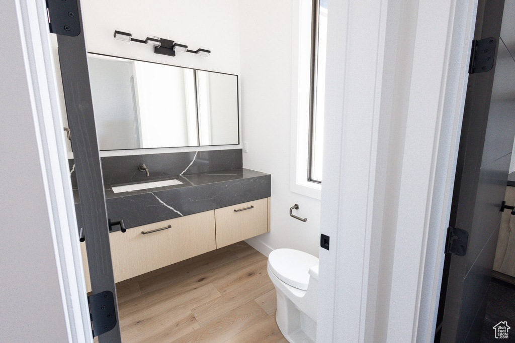 Bathroom with vanity, toilet, and wood finished floors