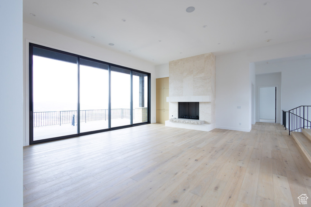 Unfurnished living room with light wood-style floors and a large fireplace