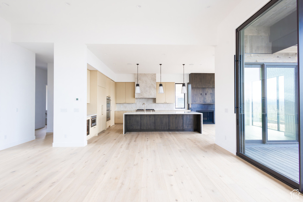 Kitchen with decorative backsplash, modern cabinets, light countertops, a sink, and light wood-style flooring
