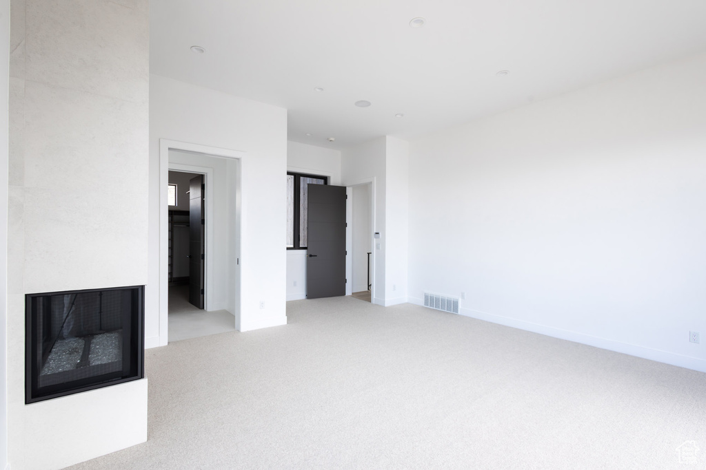 Interior space featuring a fireplace, light colored carpet, and visible vents