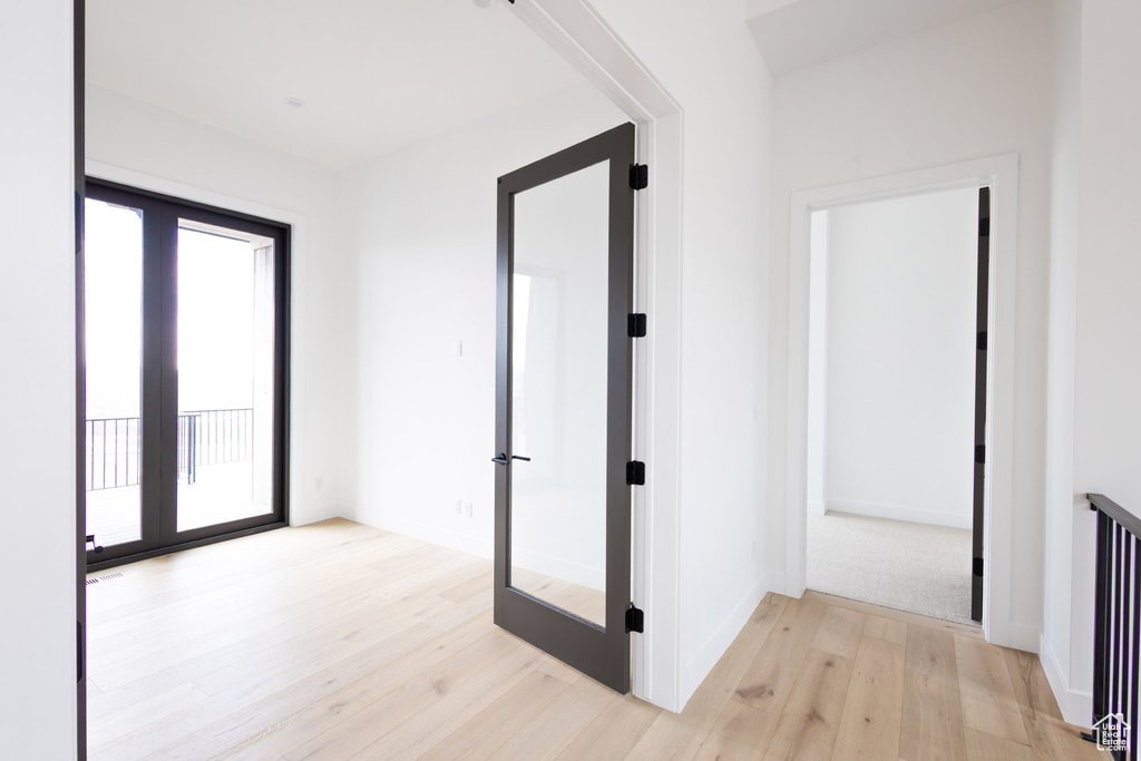 Corridor featuring french doors, light wood finished floors, and baseboards