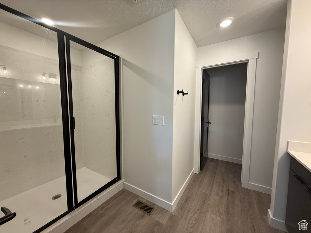 Full bath featuring baseboards, wood finished floors, visible vents, and a stall shower