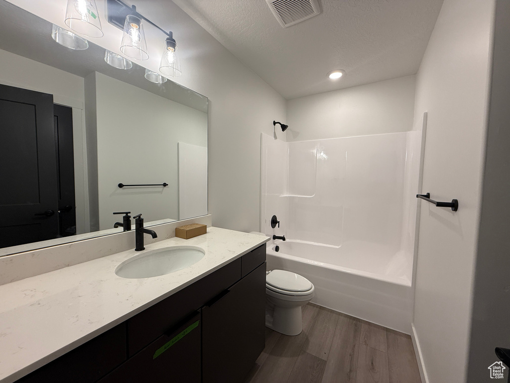 Full bath featuring vanity, wood finished floors, visible vents, bathing tub / shower combination, and toilet