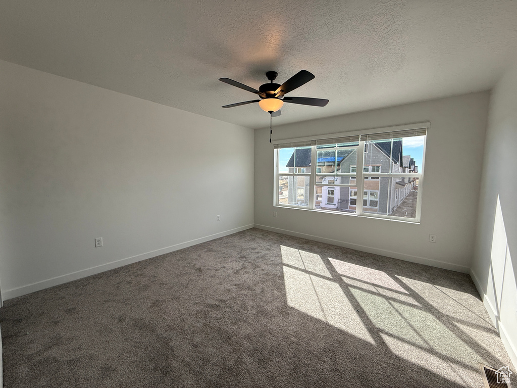 Unfurnished room featuring a ceiling fan, baseboards, visible vents, and a textured ceiling