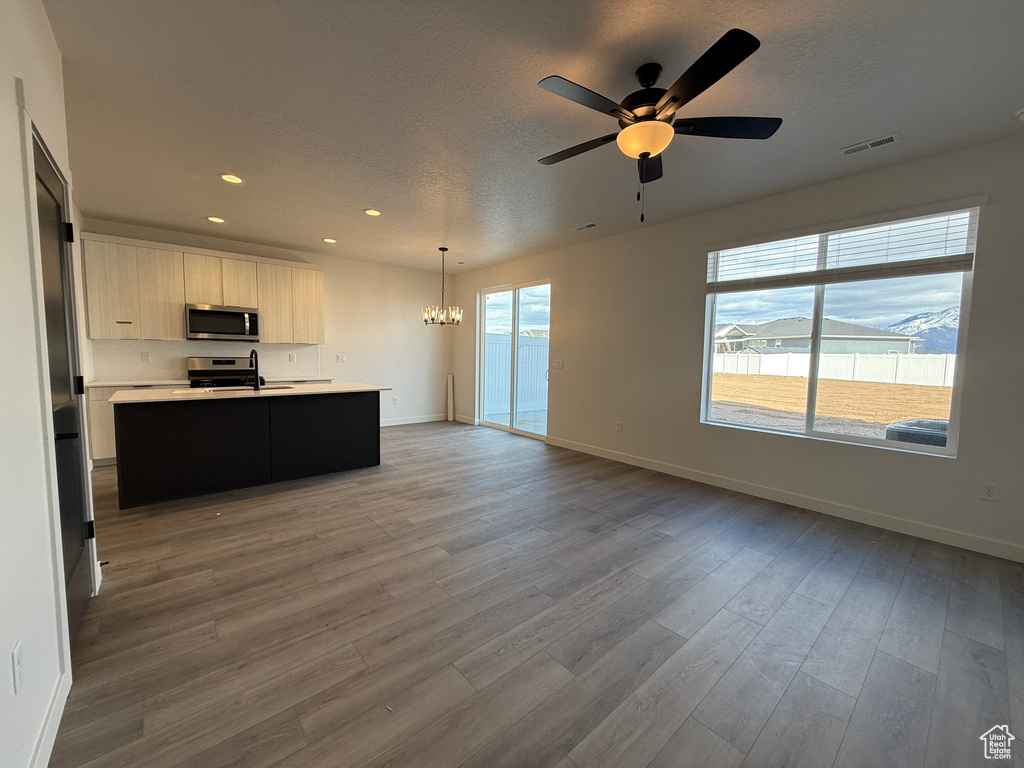 Kitchen with wood finished floors, visible vents, stainless steel appliances, light countertops, and open floor plan