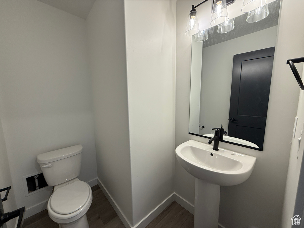 Bathroom with toilet, wood finished floors, baseboards, and a sink