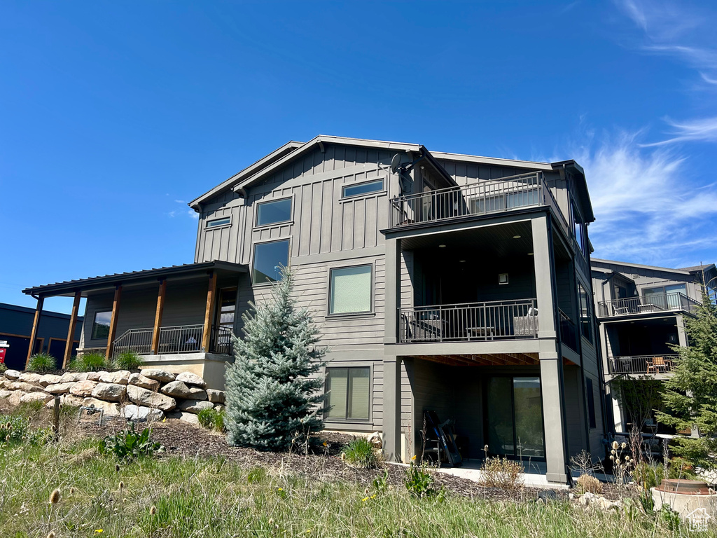 Back of house with a balcony and board and batten siding
